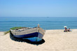old rowing boat on white sandy beach and people sunbathing next old rowing boat on white sandy beach and people sunbathing next