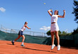 two female tennis players playing doubles in the sun. one is lea two female tennis players playing doubles in the sun. one is lea