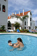 young mother playing in children's swimming pool with toddler so