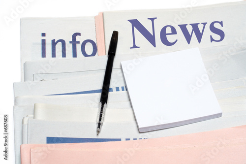 note and pen, over stacked newspapers