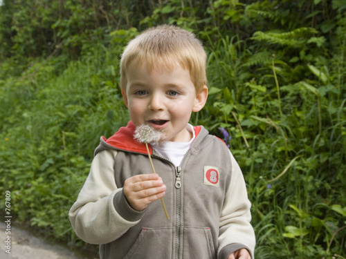 Photo: young boy blowing dandelion seeds. young boy blowing dandelion seeds.