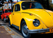 a vintage red and yellow  volkswagen beetle parked