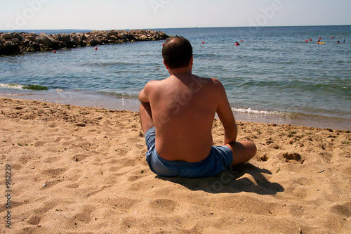 Photo: man sitting on beach man sitting on beach