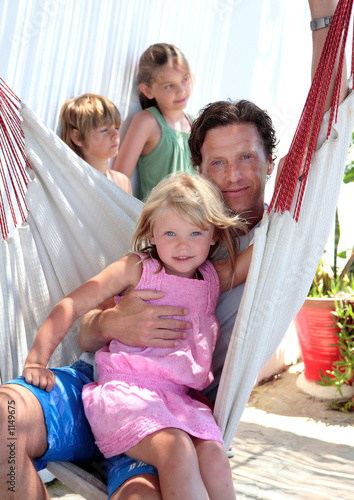 Photo: young father and children sitting in a hammock on vacation young father and children sitting in a hammock on vacation