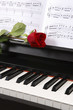 piano with sheet music and a rose