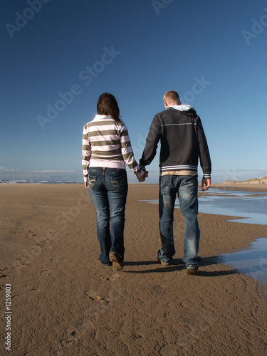 2 people holding hands at beach. couple holding hands on each