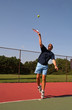 young man serving tennis ball