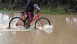 boy cycling through flood