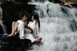 couple sitting in waterfall couple sitting in waterfall