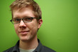 man with glasses against green wall
