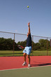 young man serving tennis ball