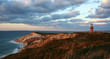 Leinwandbild Motiv sunset over red cliffs and lighthouse