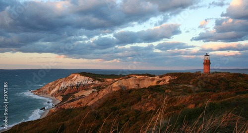 Leinwandbild Motiv sunset over red cliffs and lighthouse