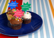 three chocolate frosted cupcakes on a blue plate with "happy bir