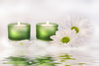 green candles and daisies near water reflection