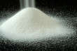 sugar falls on a mountain of granulated sugar on a black backgro sugar falls on a mountain of granulated sugar on a black backgro