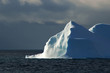 sunlit white-blue iceberg with dark sky