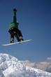 snowboarder in green jacket juping high - winter mountain action