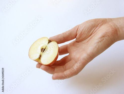 Photo: a female hand holding a part of an apple a female hand holding a part of an apple