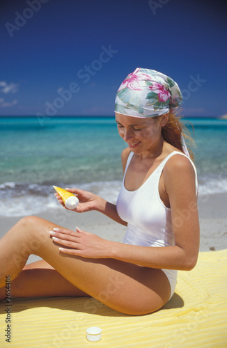 donna si mette la crema al mare