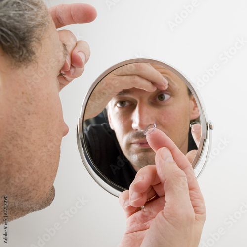 man inserting a contact lens in his eye man inserting a contact lens in his eye
