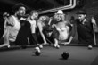 retro group trying to distract man as he takes pool shot.