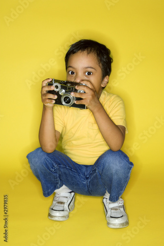 Photo: Male child kneeling with camera. Male child kneeling with camera.