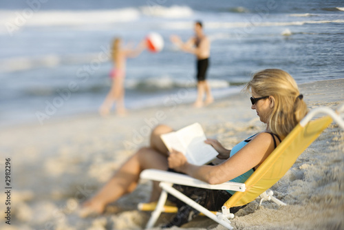 Photo: Mom reading in lounge chair on beach. Mom reading in lounge chair on beach.