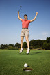 Photo : Woman jumping for joy over good golf shot.