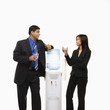 businessman and businesswoman conversing at water cooler.