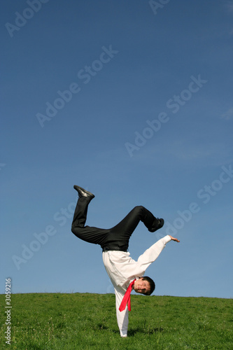 businessman doing one handed handstand outdoors