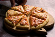 Cutting in pieces cheese pizza on wooden plate