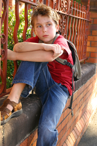 Photo: boy with schoolbag slung over shoulder boy with schoolbag slung over shoulder