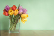 vase of tulips on table - green background