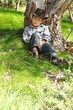 A boy from the bush sits under  an Australian gum tree.