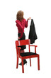 Attractive girl near red chair holding her black jacket