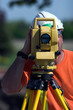A surveyor at a construction site peering through a level