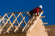 Carpenter building a roof of a house at a construction site.