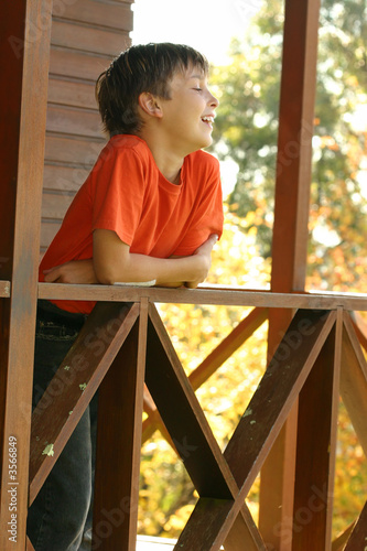 Photo: Happy child leaning on the porch balustrade Happy child leaning on the porch balustrade