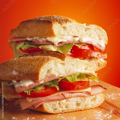 Photo: Tasty ham and tomato sandwich on a wooden table Tasty ham and tomato sandwich on a wooden table