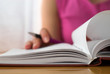 Young female is writing notes and planning her schedule.