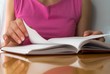 Young female opens notebook and planning her schedule.