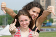 Two teen girls show thumbs up signs