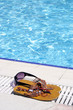 glasses, watch and sandal lying by the swimming pool.