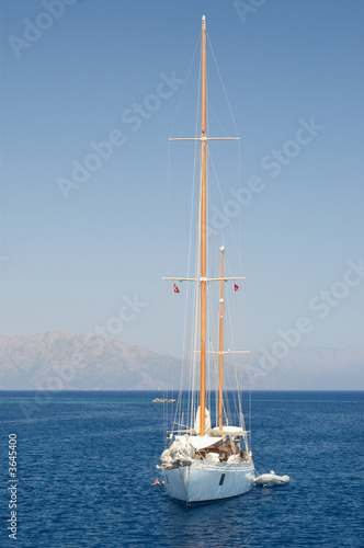 Solitary Yacht at sea against mountains