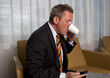 A man in shirt and tie reading a email and drinking coffee