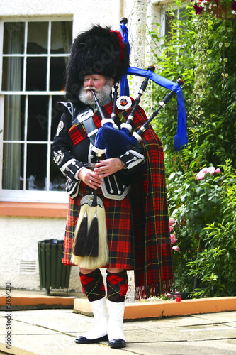 A Scottish bagpiper in full highland kilt dress and beard