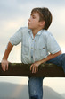 Boy climbs up onto a fence.