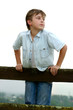 Child standing on a timber fence on an overcast afternoon.