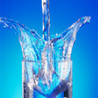 Pouring water in glass with a splash